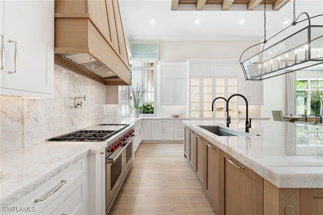 kitchen featuring light stone countertops, sink, range with two ovens, white cabinets, and light wood-type flooring