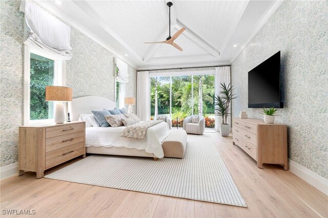 bedroom with light hardwood / wood-style floors, ceiling fan, and a tray ceiling