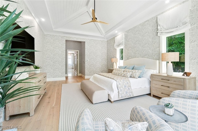 bedroom with multiple windows, ceiling fan, beamed ceiling, and light wood-type flooring