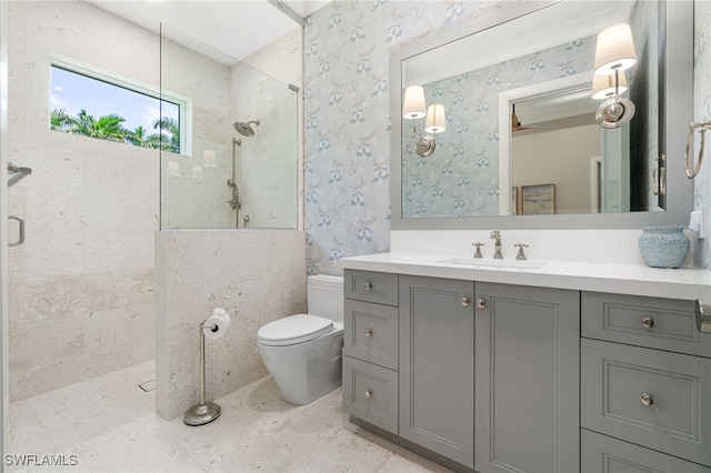 bathroom with a tile shower, vanity, and toilet