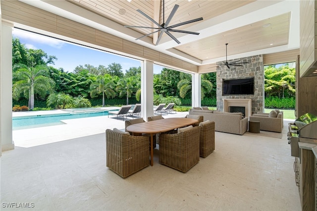 view of patio with an outdoor living space with a fireplace, area for grilling, and ceiling fan