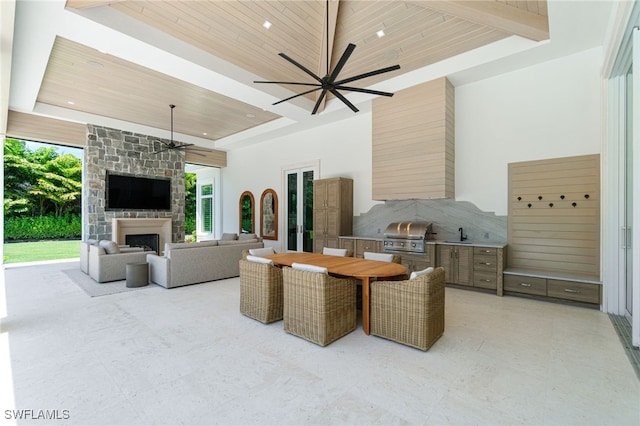 living room featuring an outdoor stone fireplace, wood ceiling, a high ceiling, and a wealth of natural light