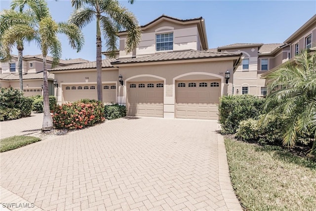 mediterranean / spanish-style home with a tile roof, stucco siding, and decorative driveway