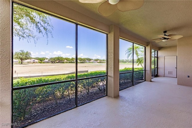 unfurnished sunroom featuring ceiling fan