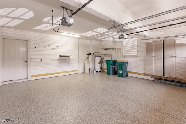 garage with a garage door opener, water heater, and baseboards
