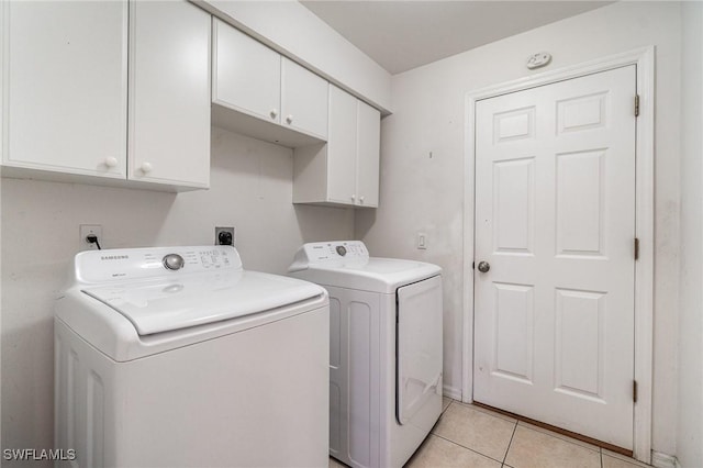 washroom with washer and dryer, cabinets, and light tile patterned floors