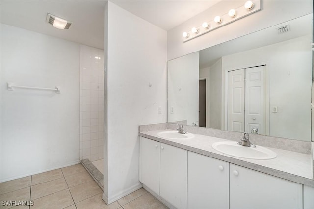 bathroom featuring a tile shower, tile patterned flooring, and vanity