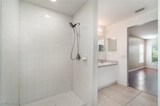 bathroom with tile patterned flooring, vanity, and a tile shower