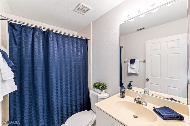 bathroom featuring a textured ceiling, vanity, toilet, and a shower with curtain