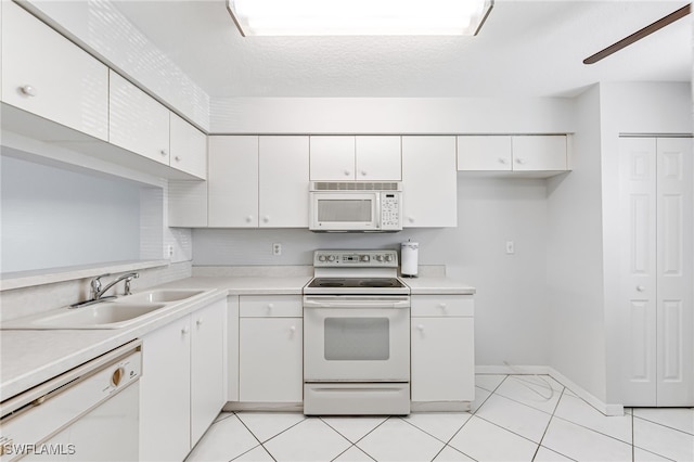 kitchen featuring white appliances, white cabinetry, sink, and light tile patterned flooring