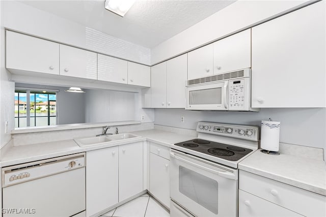 kitchen with light tile patterned flooring, sink, white appliances, a textured ceiling, and white cabinetry