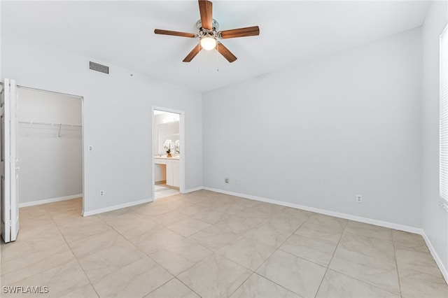 unfurnished bedroom featuring a spacious closet, ceiling fan, ensuite bath, and a closet