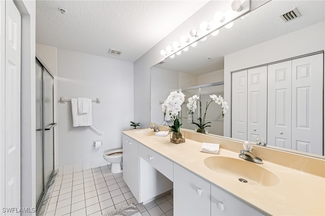 bathroom with a shower with shower door, vanity, a textured ceiling, tile patterned flooring, and toilet