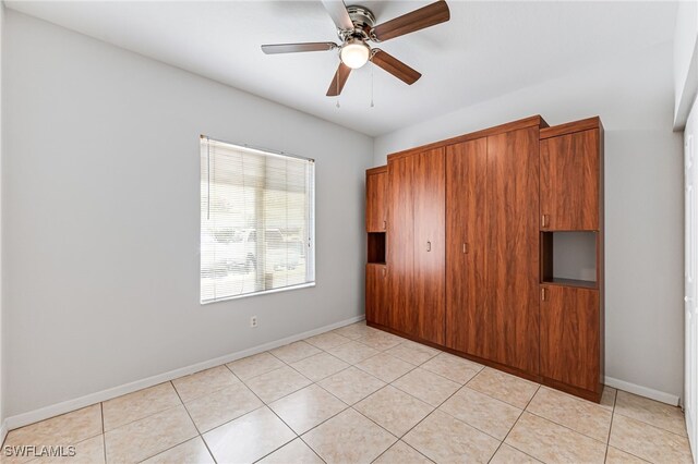 tiled empty room featuring ceiling fan