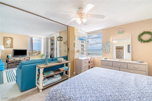 bedroom with a textured ceiling, light colored carpet, and ceiling fan