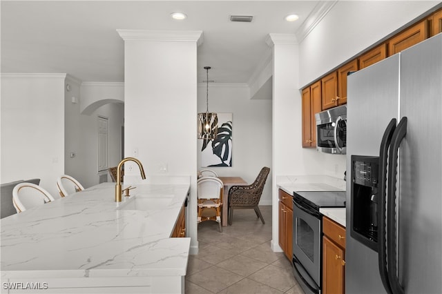 kitchen with light tile patterned flooring, sink, ornamental molding, decorative light fixtures, and stainless steel appliances