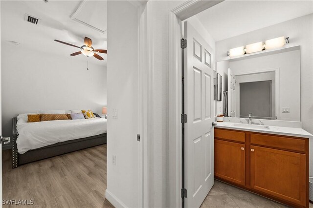 bedroom with ceiling fan, light hardwood / wood-style floors, sink, and ensuite bathroom