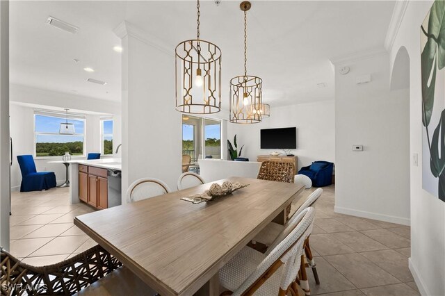 dining area featuring sink, ornamental molding, an inviting chandelier, and light tile patterned floors