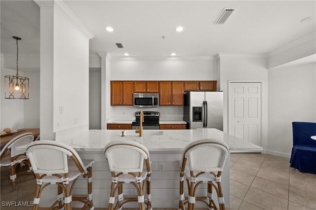 kitchen featuring appliances with stainless steel finishes, ornamental molding, light stone countertops, light tile patterned floors, and hanging light fixtures