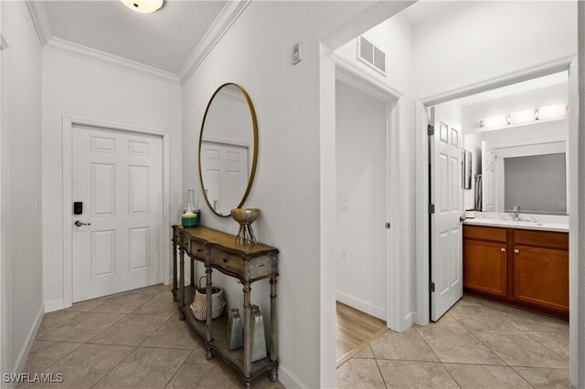 tiled foyer featuring sink and ornamental molding