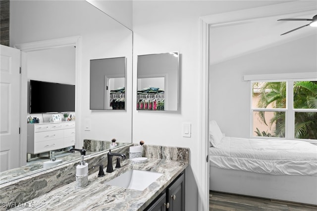 bathroom with ceiling fan, vaulted ceiling, wood-type flooring, and vanity