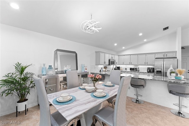 tiled dining space featuring vaulted ceiling and an inviting chandelier