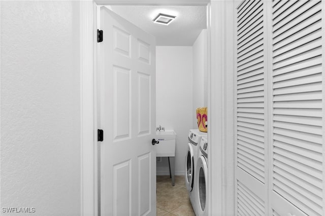 clothes washing area featuring independent washer and dryer, a textured ceiling, light tile patterned floors, and sink