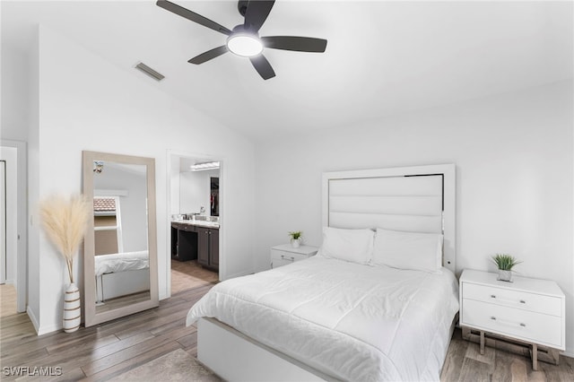 bedroom with ceiling fan, light wood-type flooring, vaulted ceiling, and ensuite bath