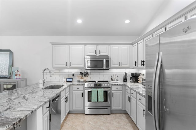 kitchen featuring decorative backsplash, light stone counters, light tile patterned floors, sink, and stainless steel appliances