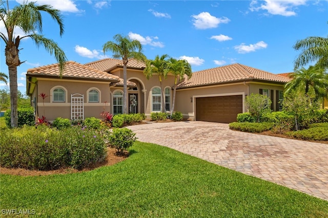 mediterranean / spanish house featuring a garage and a front yard