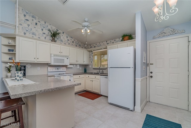 kitchen with kitchen peninsula, a kitchen breakfast bar, white appliances, sink, and lofted ceiling