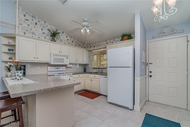 kitchen with white appliances, lofted ceiling, a kitchen breakfast bar, a peninsula, and a sink