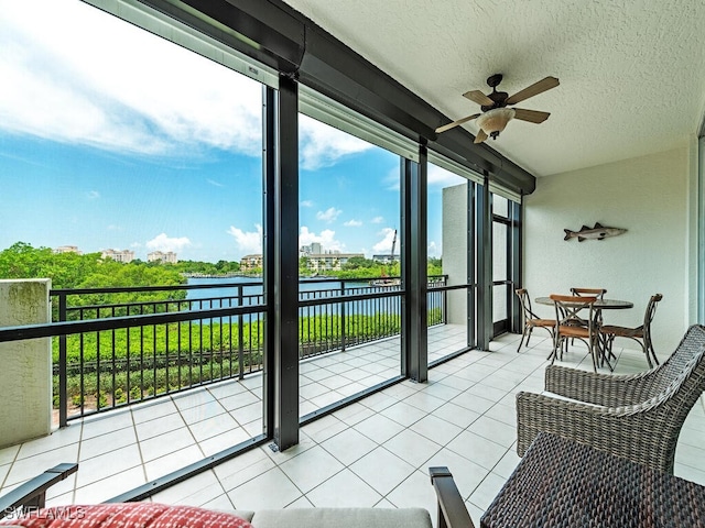 sunroom / solarium with a water view and a ceiling fan