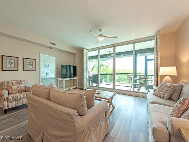 living room with ceiling fan, expansive windows, visible vents, and wood finished floors