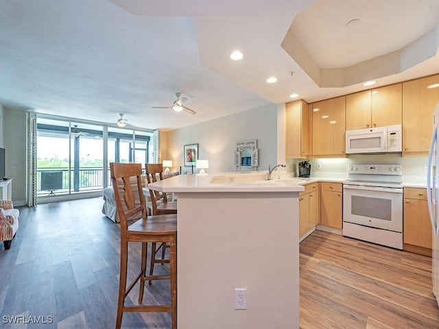 kitchen featuring ceiling fan, light hardwood / wood-style flooring, light brown cabinetry, kitchen peninsula, and white appliances