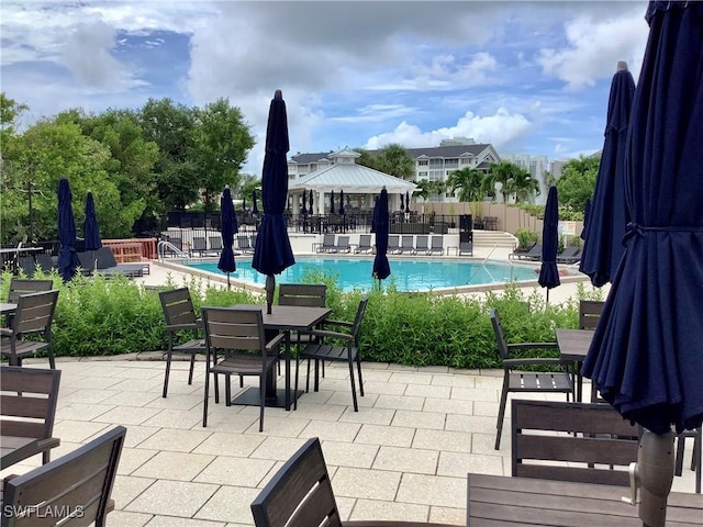 view of patio / terrace with a community pool, fence, and a gazebo