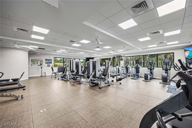 workout area featuring ceiling fan, a healthy amount of sunlight, and a drop ceiling