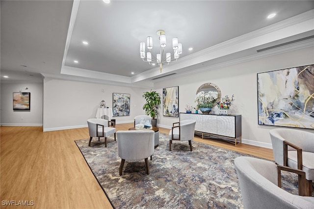 interior space featuring light wood-type flooring, a chandelier, ornamental molding, and a tray ceiling