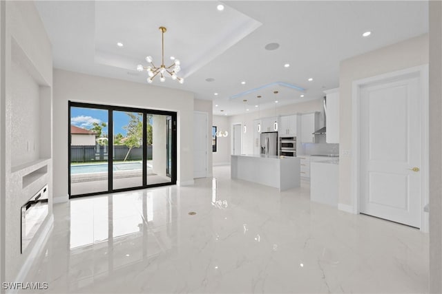 unfurnished living room with a chandelier and a raised ceiling