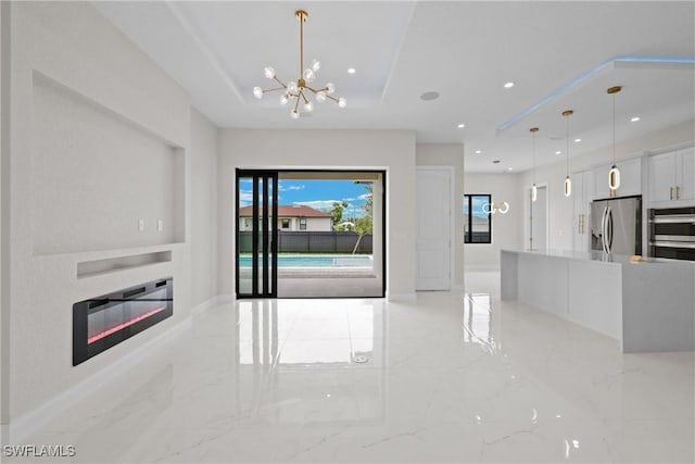 unfurnished living room featuring a raised ceiling and a chandelier