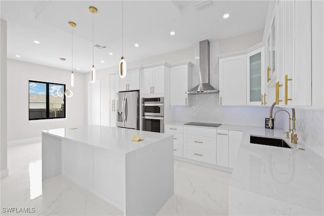 kitchen with wall chimney exhaust hood, decorative light fixtures, a kitchen island, stainless steel appliances, and white cabinets