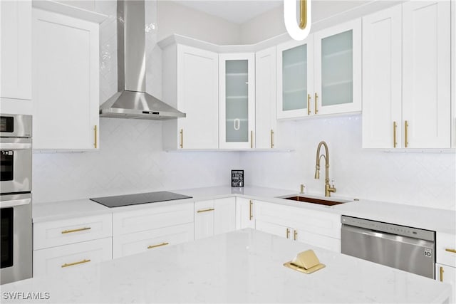 kitchen featuring appliances with stainless steel finishes, sink, white cabinets, and wall chimney exhaust hood