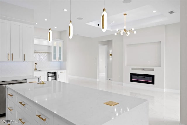 kitchen with white cabinetry, a kitchen island, pendant lighting, and light stone counters