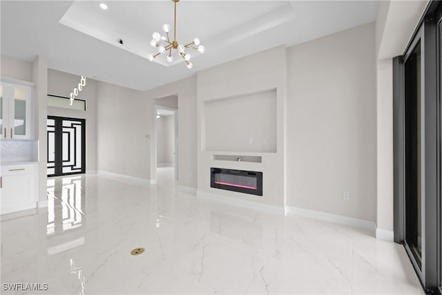 unfurnished living room with a chandelier, a raised ceiling, and french doors