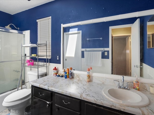 full bathroom featuring enclosed tub / shower combo, a textured ceiling, vanity, and toilet