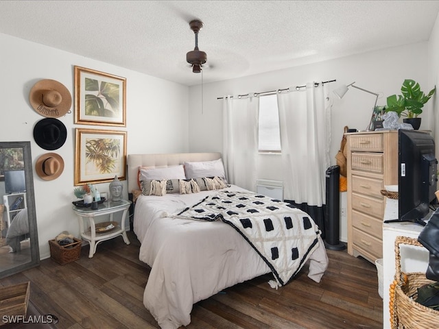 bedroom with ceiling fan, a textured ceiling, and dark wood-type flooring