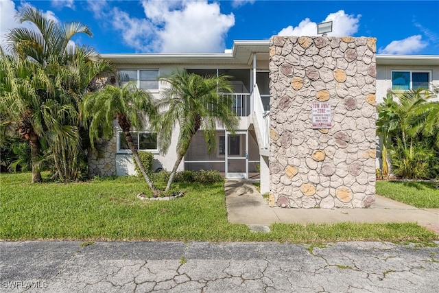 view of front facade featuring a sunroom, a front lawn, and stucco siding