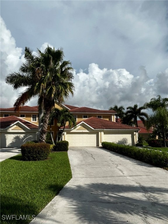 mediterranean / spanish-style house featuring a garage and a front lawn