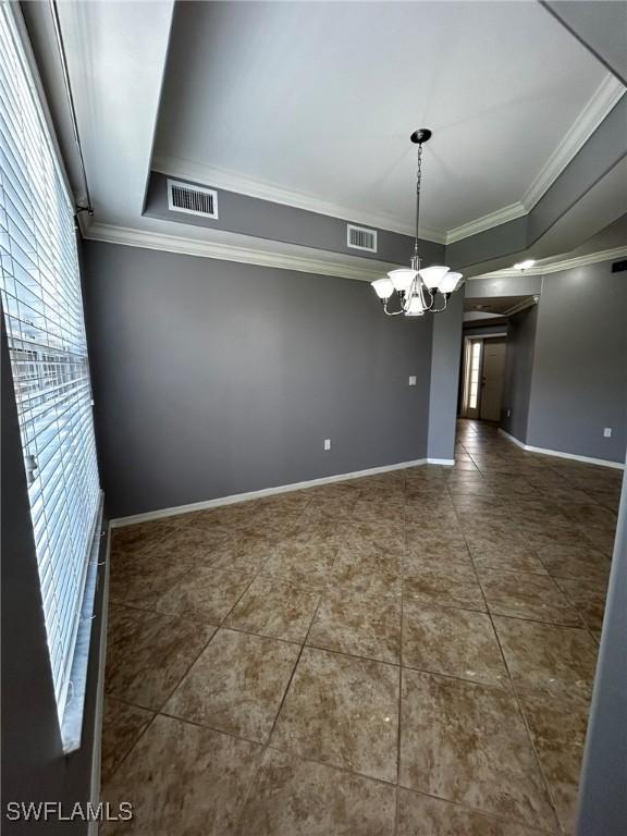 empty room featuring baseboards, crown molding, visible vents, and a notable chandelier