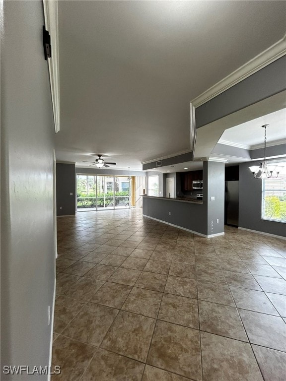 unfurnished living room with ceiling fan with notable chandelier and tile patterned flooring